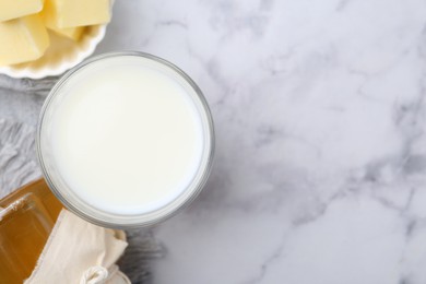 Photo of Fresh milk in glass, honey and butter on white marble table, flat lay. Space for text