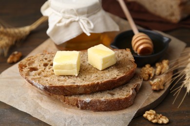 Slices of bread with butter, honey and walnuts on wooden table, closeup