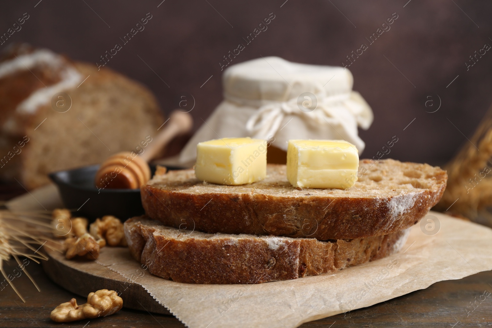 Photo of Slices of bread with butter, honey and walnuts on wooden table, closeup