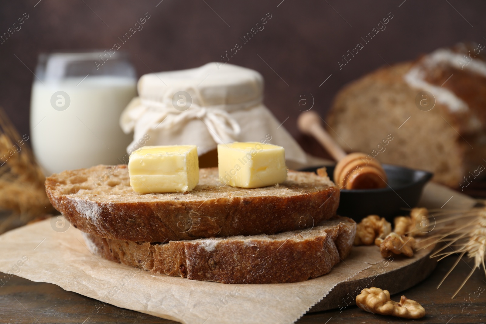 Photo of Slices of bread with butter, honey and walnuts on wooden table, closeup