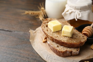 Photo of Slices of bread with butter, honey and milk on wooden table, closeup. Space for text