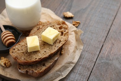 Photo of Slices of bread with butter, honey, milk and walnuts on wooden table, closeup. Space for text