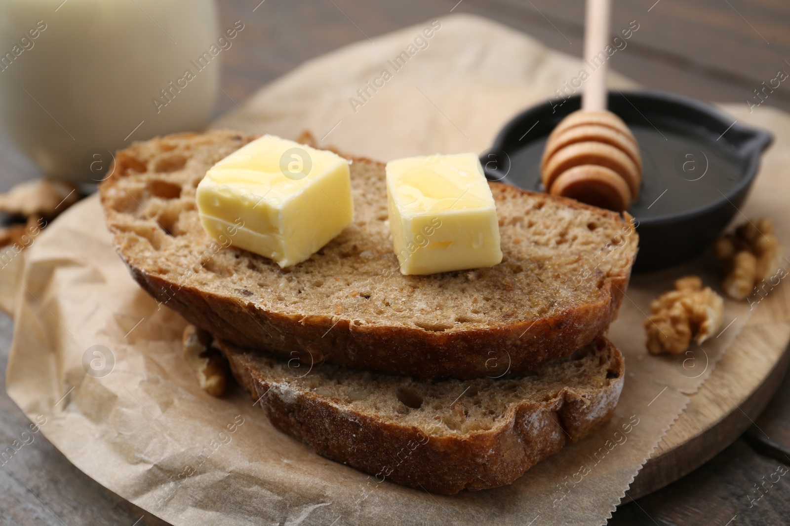 Photo of Slices of bread with butter, honey and walnuts on wooden table, closeup