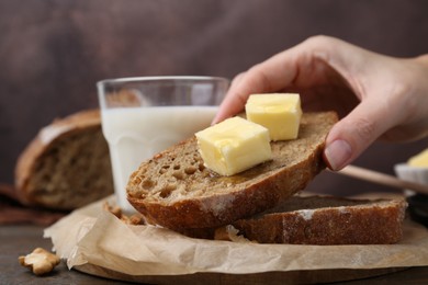 Photo of Woman holding bread slice with butter and honey at wooden table, closeup