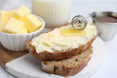 Slices of bread with butter, honey and milk on white table, closeup