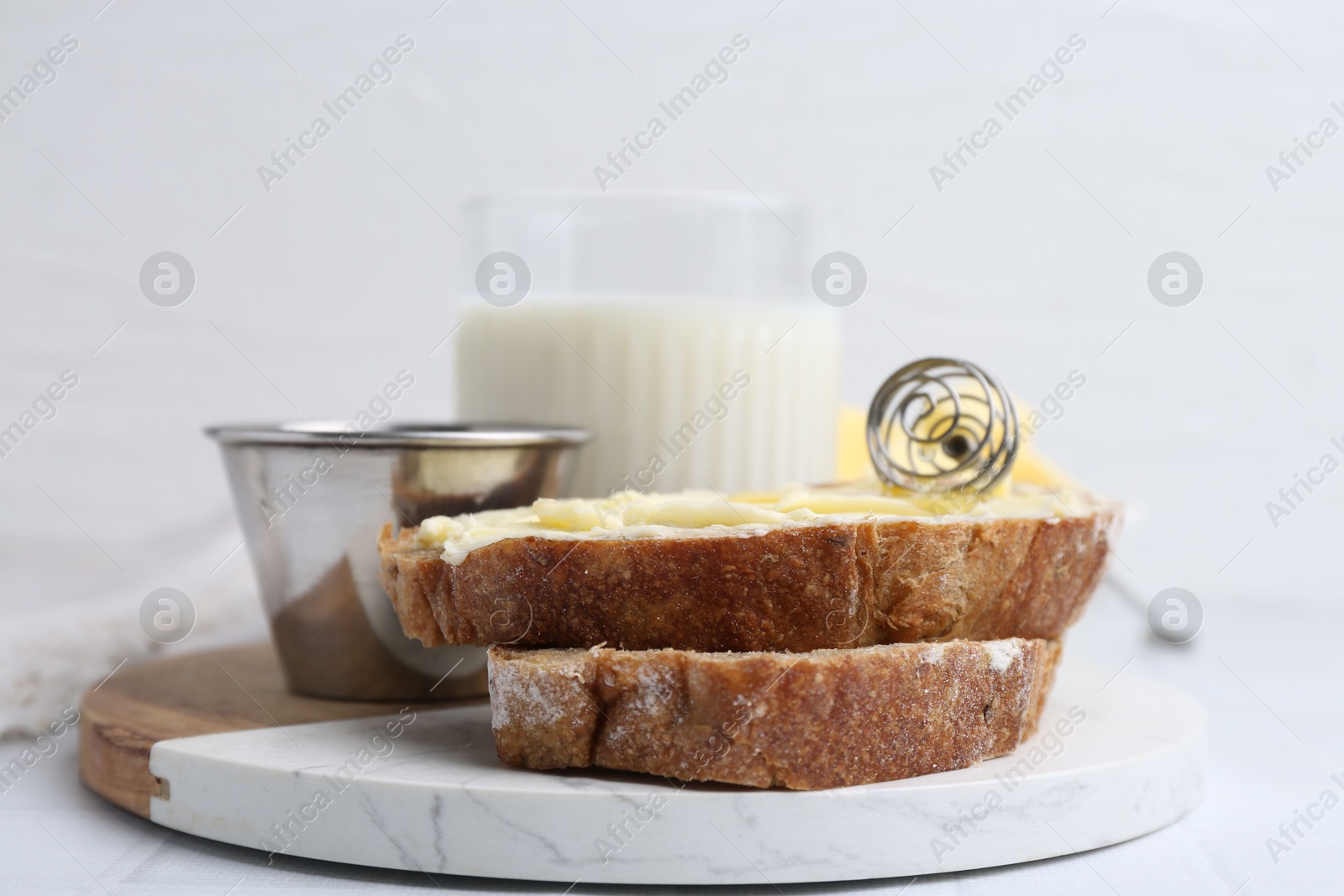 Photo of Slices of bread with butter, honey and milk on white table, closeup