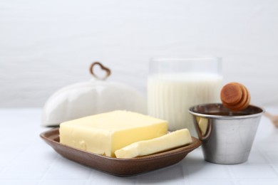 Photo of Fresh milk in glass, honey and butter on white tiled table, closeup