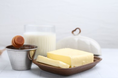 Photo of Fresh milk in glass, honey and butter on white tiled table, closeup