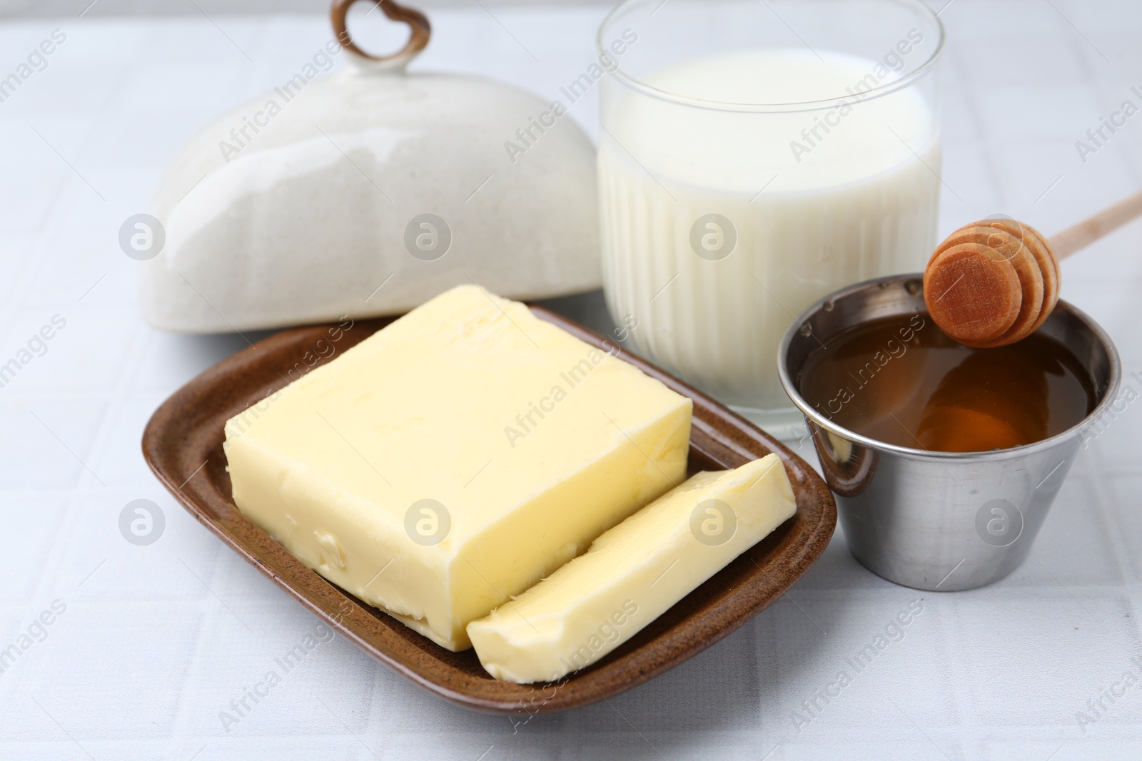 Photo of Fresh milk in glass, honey and butter on white tiled table, closeup