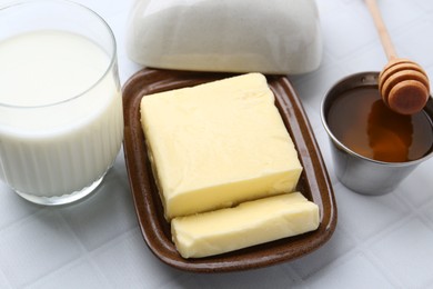 Photo of Fresh milk in glass, butter and honey on white tiled table, closeup