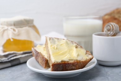 Slices of bread with butter, honey and milk on light grey table, closeup