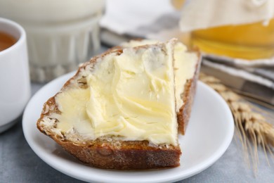 Photo of Slices of bread with butter, honey, milk and spike on light grey table, closeup