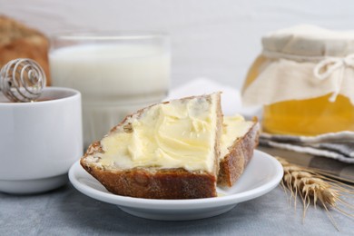 Photo of Slices of bread with butter, honey, milk and spike on light grey table, closeup