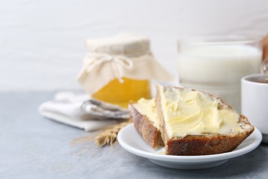 Slices of bread with butter, honey and milk on light grey table, closeup. Space for text