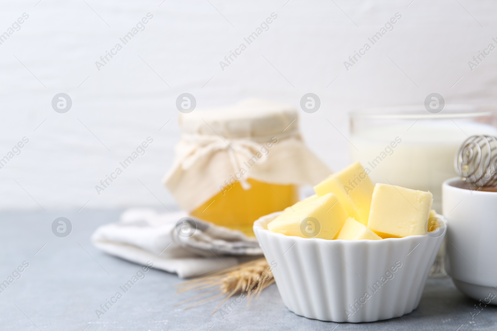 Photo of Fresh butter, honey and milk on light grey table, closeup. Space for text