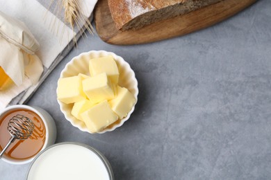 Fresh butter, milk, honey and bread on grey table, flat lay. Space for text