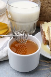 Photo of Honey, milk and bread on grey table, closeup