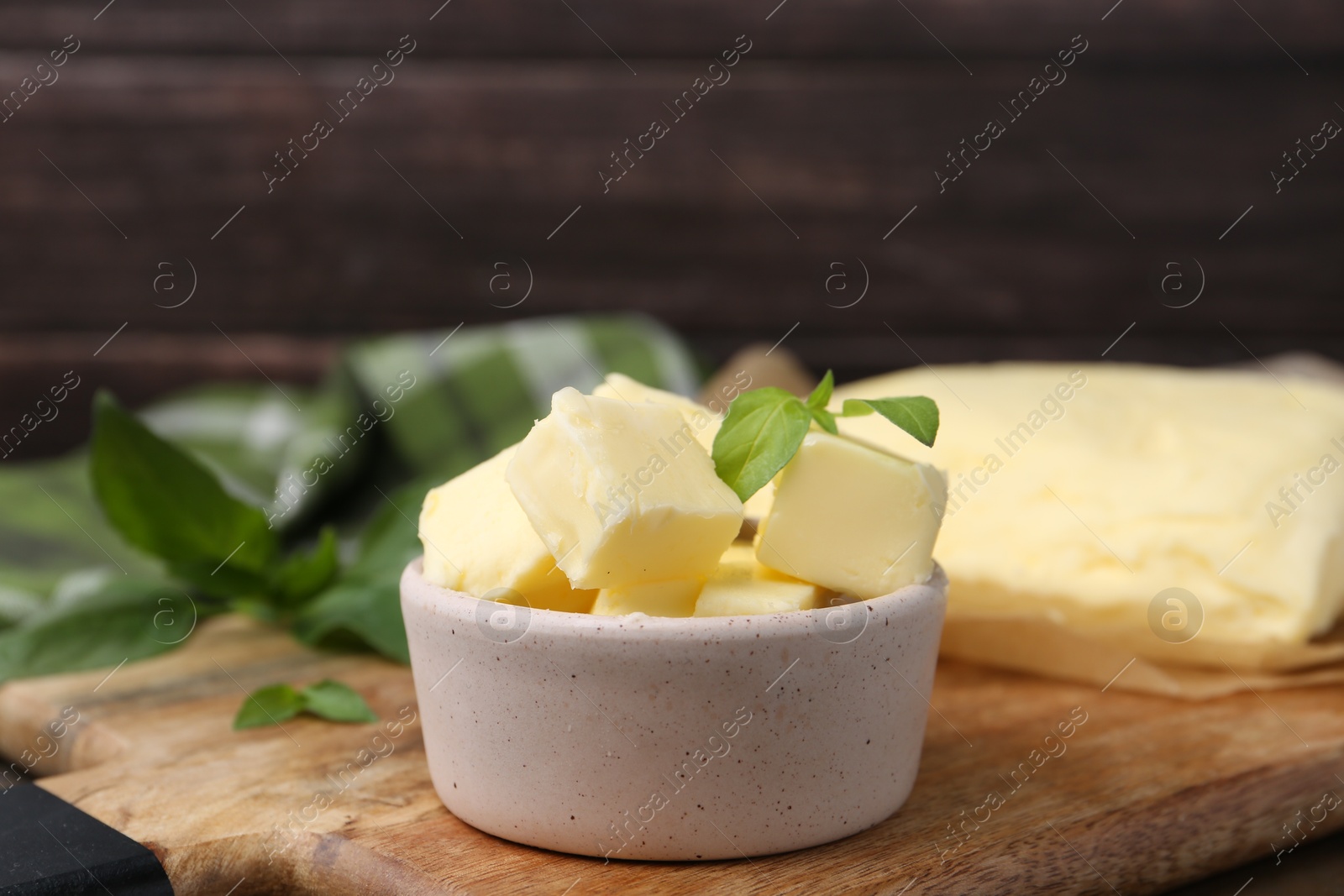 Photo of Pieces of butter on wooden board, closeup