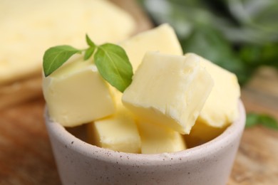 Photo of Pieces of butter with basil on table, closeup