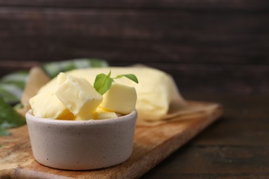 Photo of Pieces of butter on wooden table, closeup. Space for text