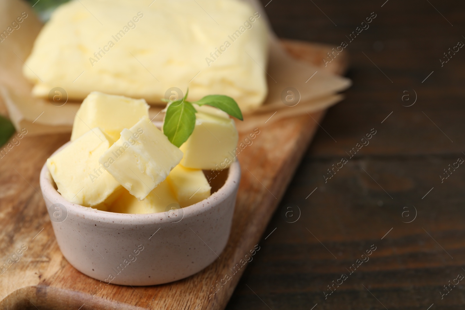 Photo of Pieces of butter on wooden table, closeup. Space for text