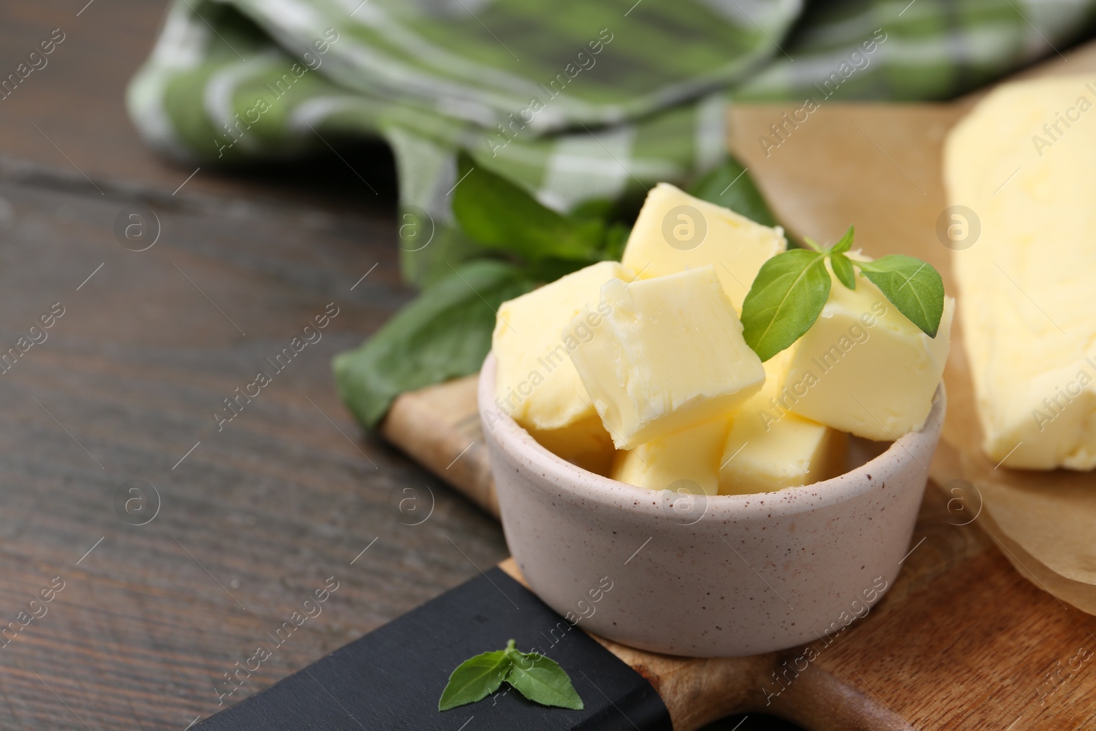 Photo of Pieces of butter on wooden table, closeup. Space for text