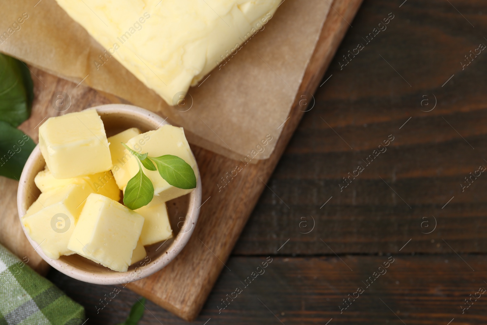 Photo of Pieces of butter on wooden table, top view. Space for text