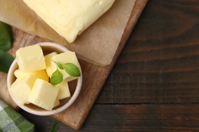 Photo of Pieces of butter on wooden table, top view. Space for text