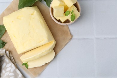 Photo of Cut butter and basil on white tiled table, flat lay. Space for text