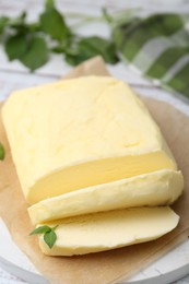 Cut brick of butter and basil on table, closeup