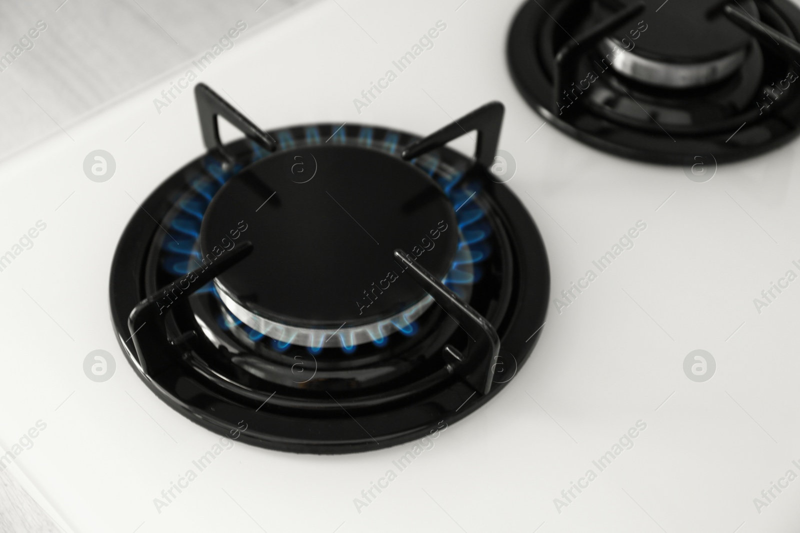 Photo of Gas burner of modern stove with burning blue flame, above view