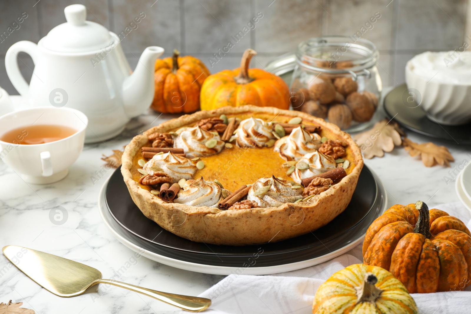 Photo of Homemade pumpkin pie with whipped cream, seeds and cinnamon on white marble table