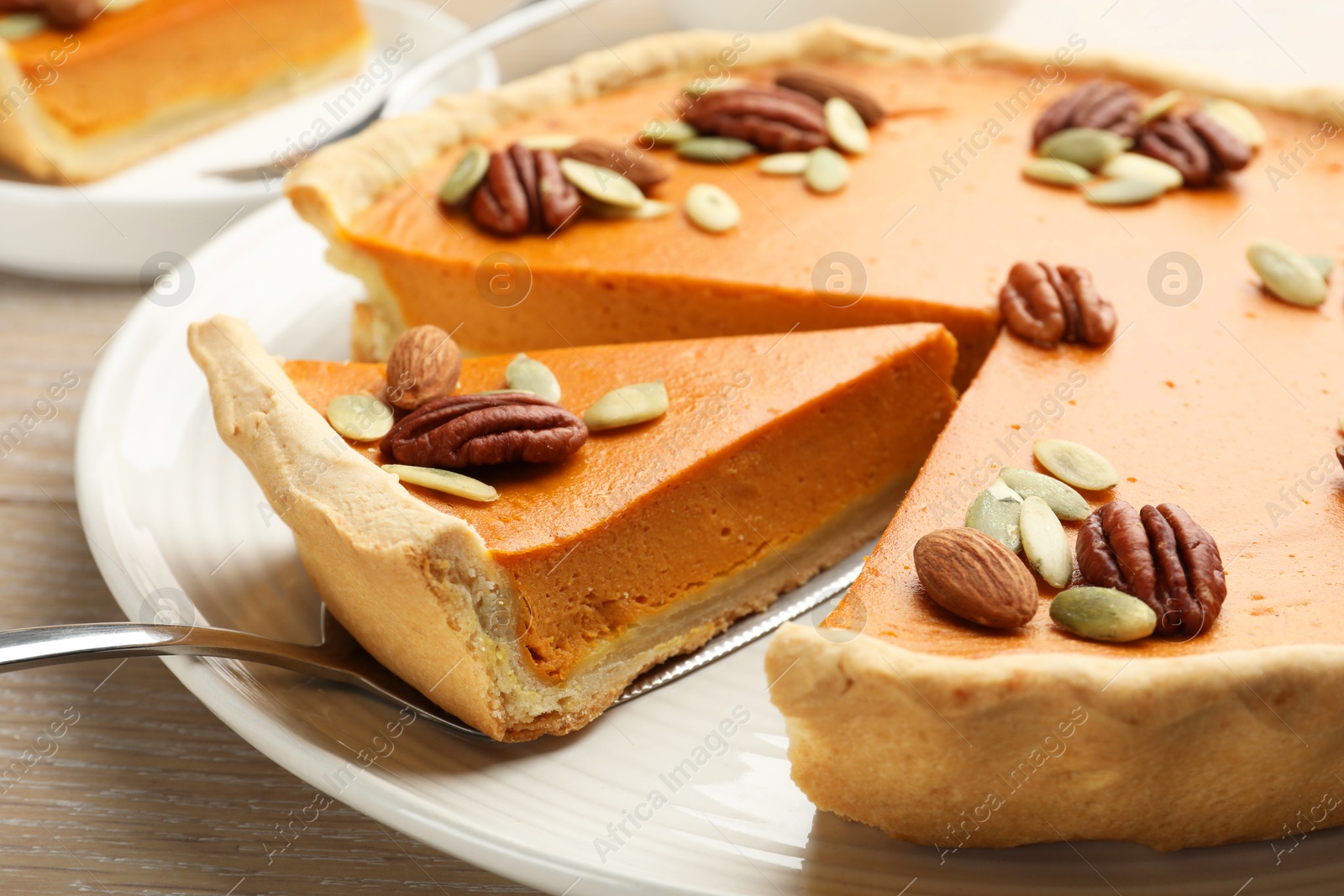 Photo of Taking piece of tasty homemade pumpkin pie at wooden table, closeup