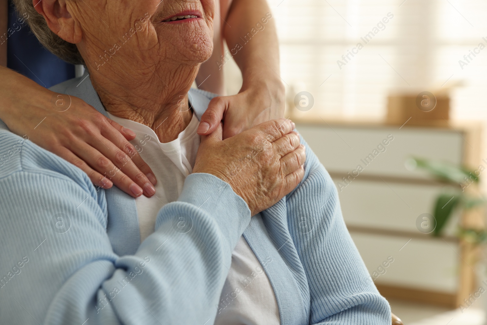 Photo of Caregiver supporting senior woman indoors, closeup. Home health care service