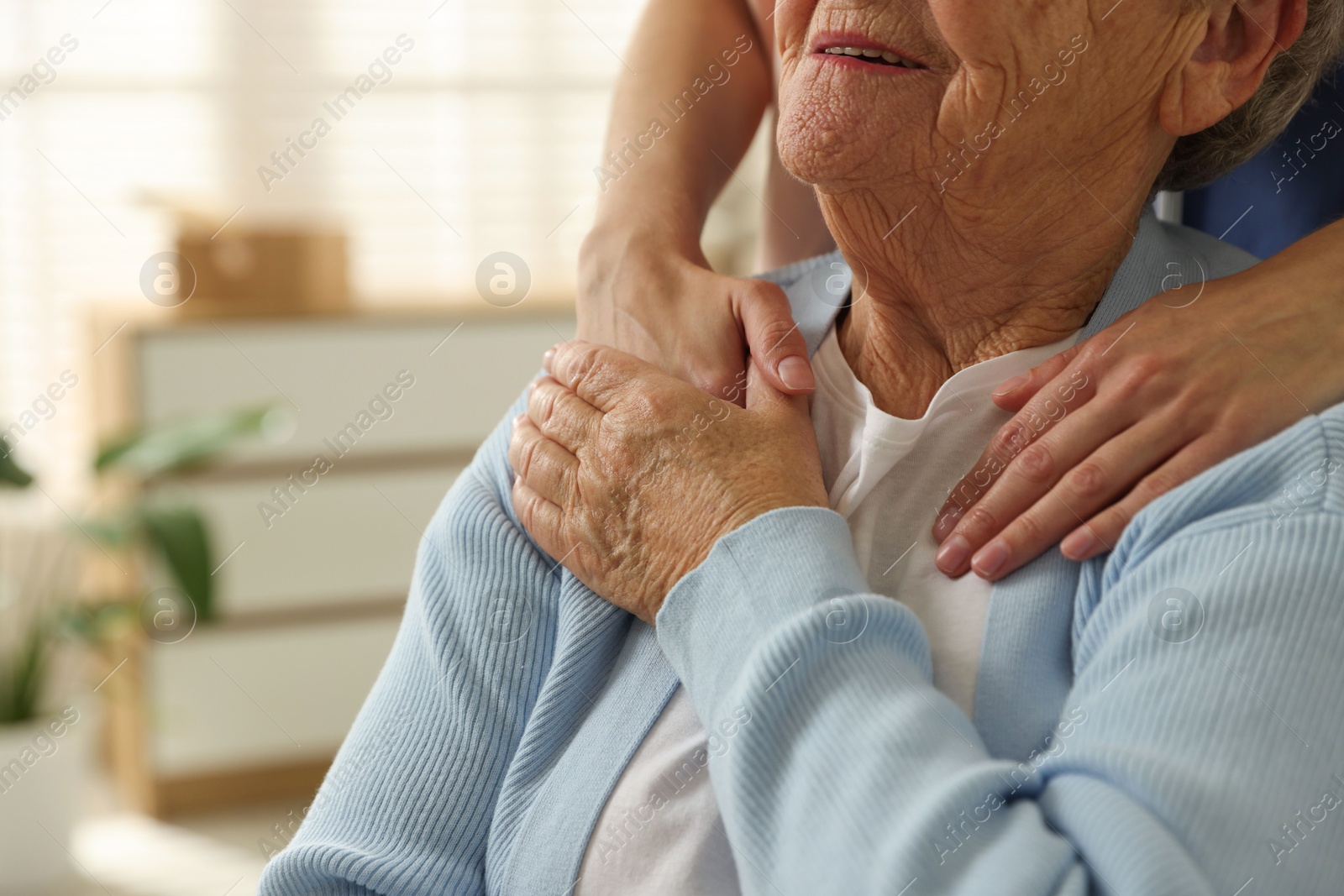 Photo of Caregiver supporting senior woman indoors, closeup. Home health care service