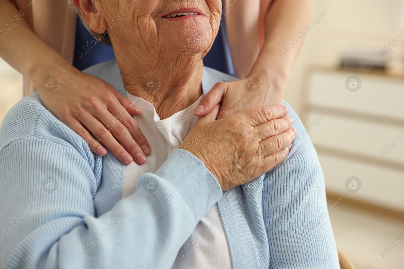 Photo of Caregiver supporting senior woman indoors, closeup. Home health care service