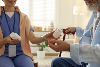 Caregiver giving pills to senior man indoors, closeup. Home health care service