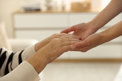 Caregiver supporting senior woman indoors, closeup. Home health care service