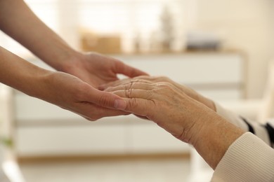 Photo of Caregiver supporting senior woman indoors, closeup. Home health care service