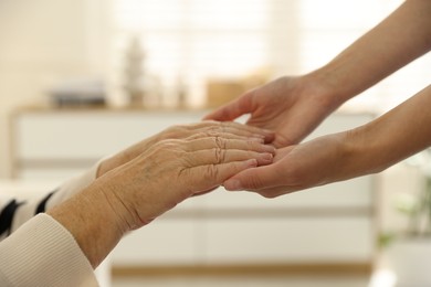 Photo of Caregiver supporting senior woman indoors, closeup. Home health care service