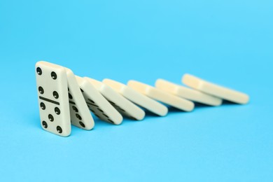 Photo of Domino effect. Tiles falling on light blue background