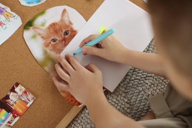 Photo of Creating vision board. Little boy drawing on paper indoors, closeup