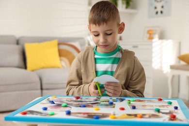 Photo of Creating vision board. Little boy cutting out picture at table indoors