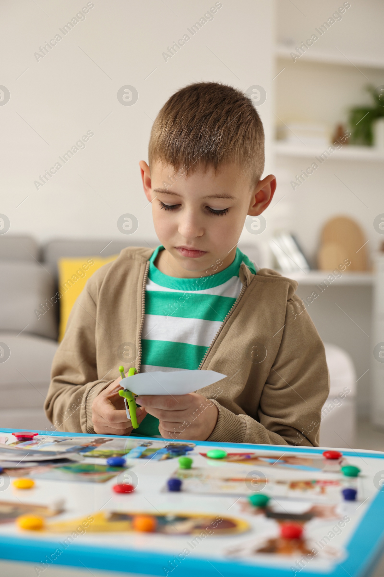 Photo of Creating vision board. Little boy cutting out picture at table indoors