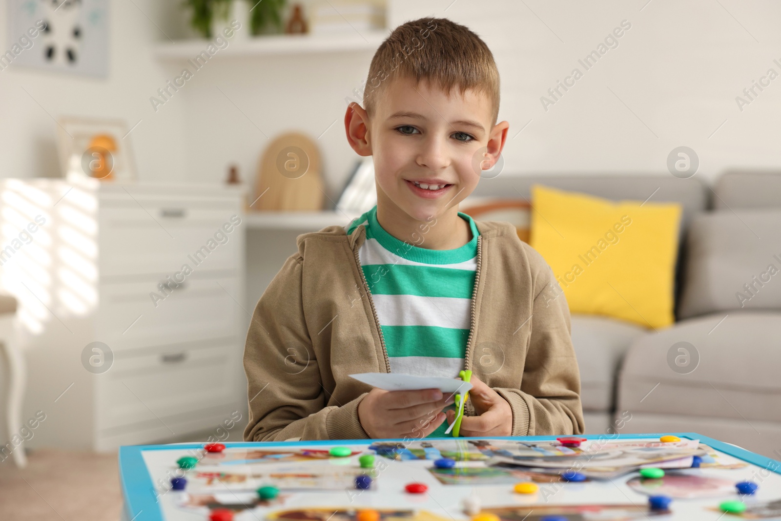 Photo of Creating vision board. Little boy cutting out picture at table indoors