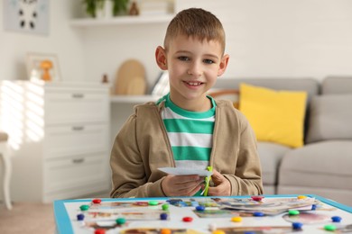 Photo of Creating vision board. Little boy cutting out picture at table indoors