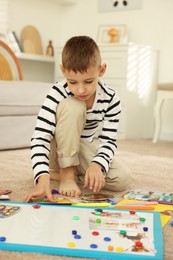 Photo of Little boy creating vision board with different pictures and other elements on floor at home