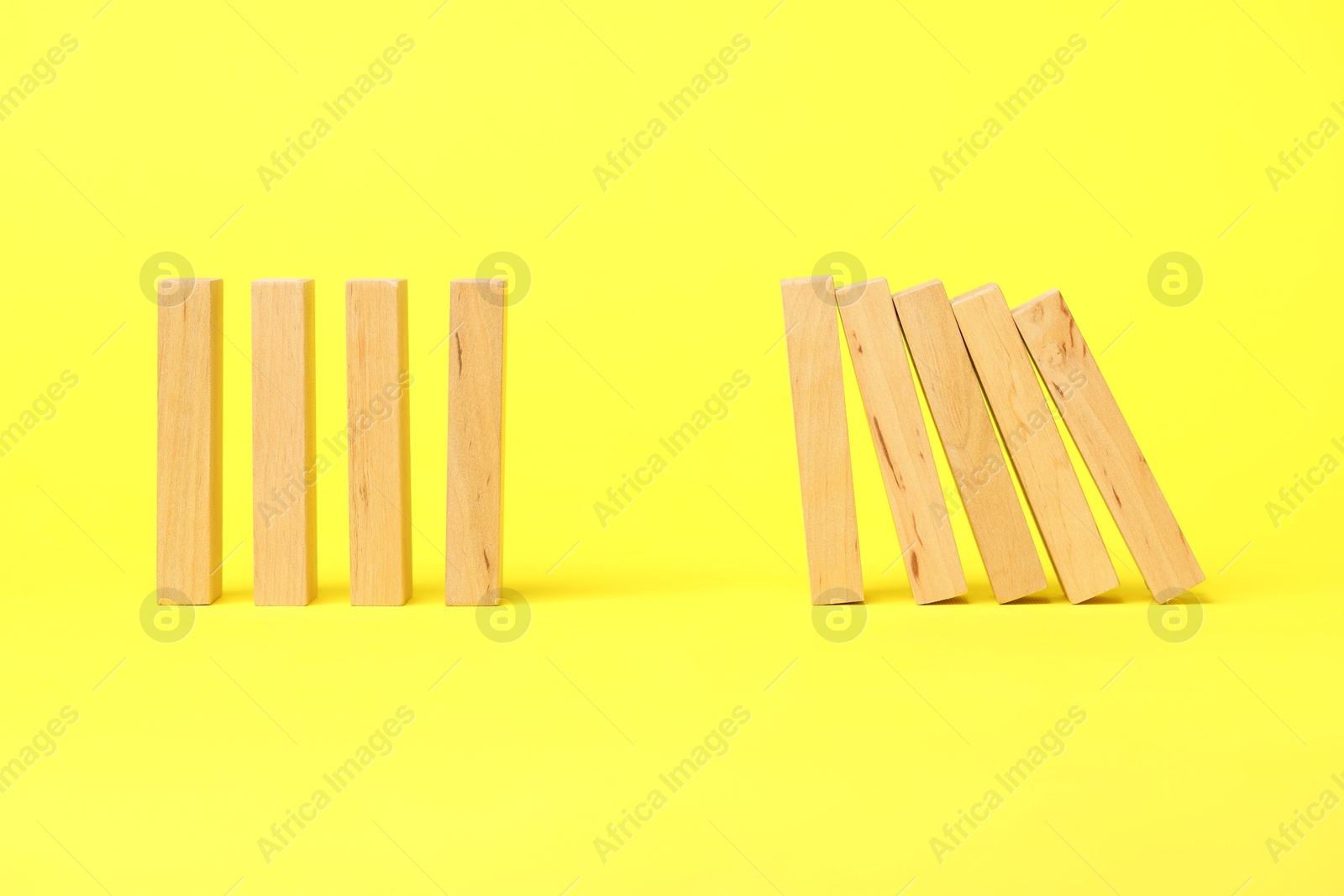 Photo of Domino effect. Wooden blocks falling on yellow background