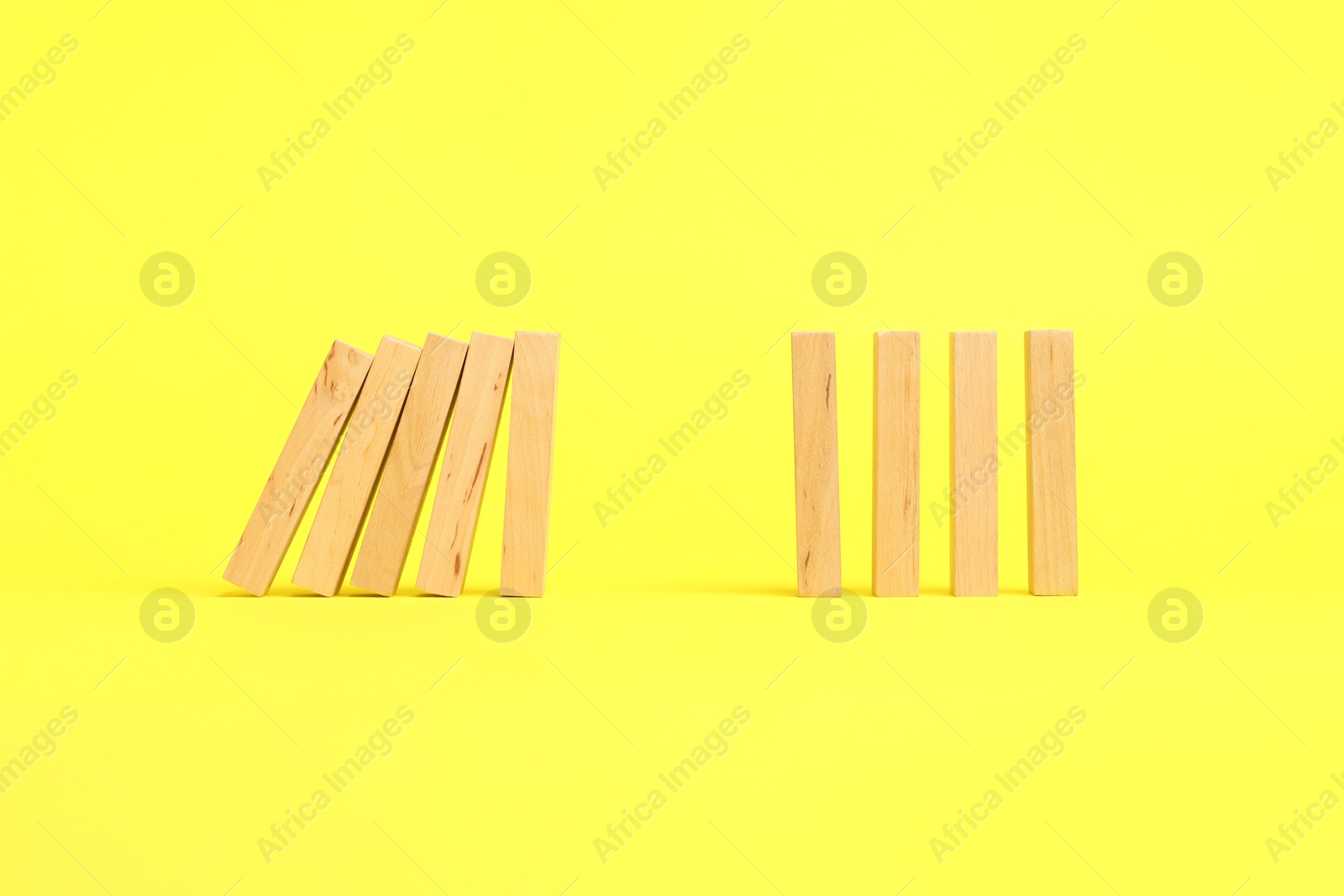 Photo of Domino effect. Wooden blocks falling on yellow background. Space for text