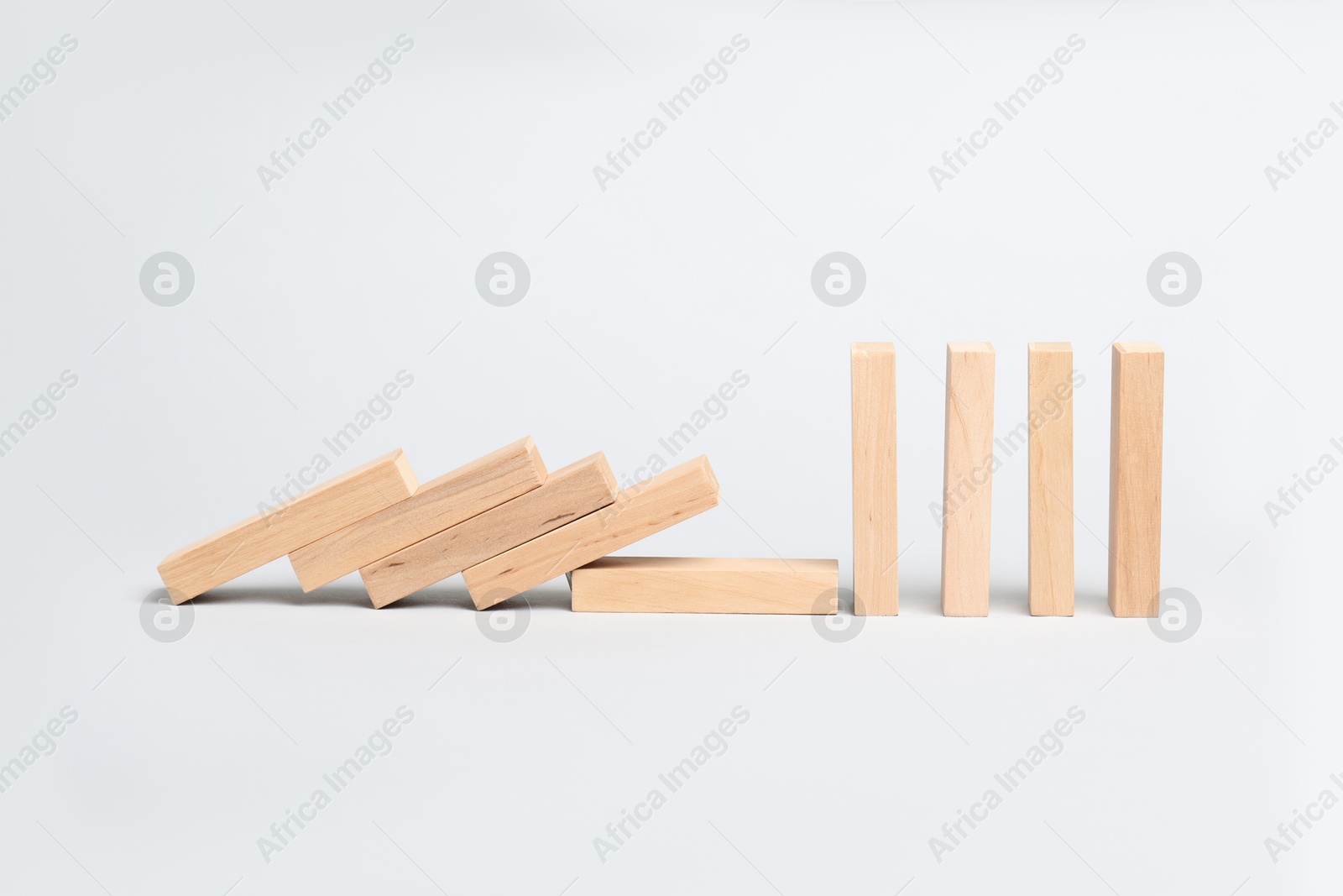 Photo of Domino effect. Wooden blocks falling on light background